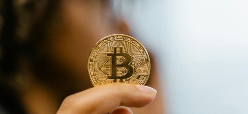 A hand holding a Bitcoin coin, representing cryptocurrency and blockchain technology investment.