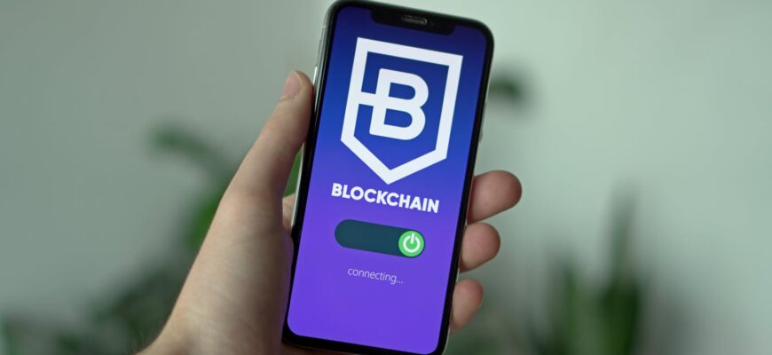 Close-up of a hand holding a smartphone with a blockchain app interface.