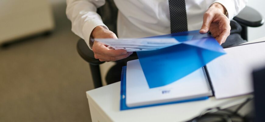 a man in a white shirt and tie holding a folder